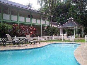 Alberca al aire libre, alberca con cascada y sombrillas en la alberca