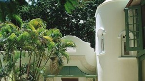 A building with a curved facade, a green door, and a fountain in the entrance. - Green Monkey Villa (Holetown)