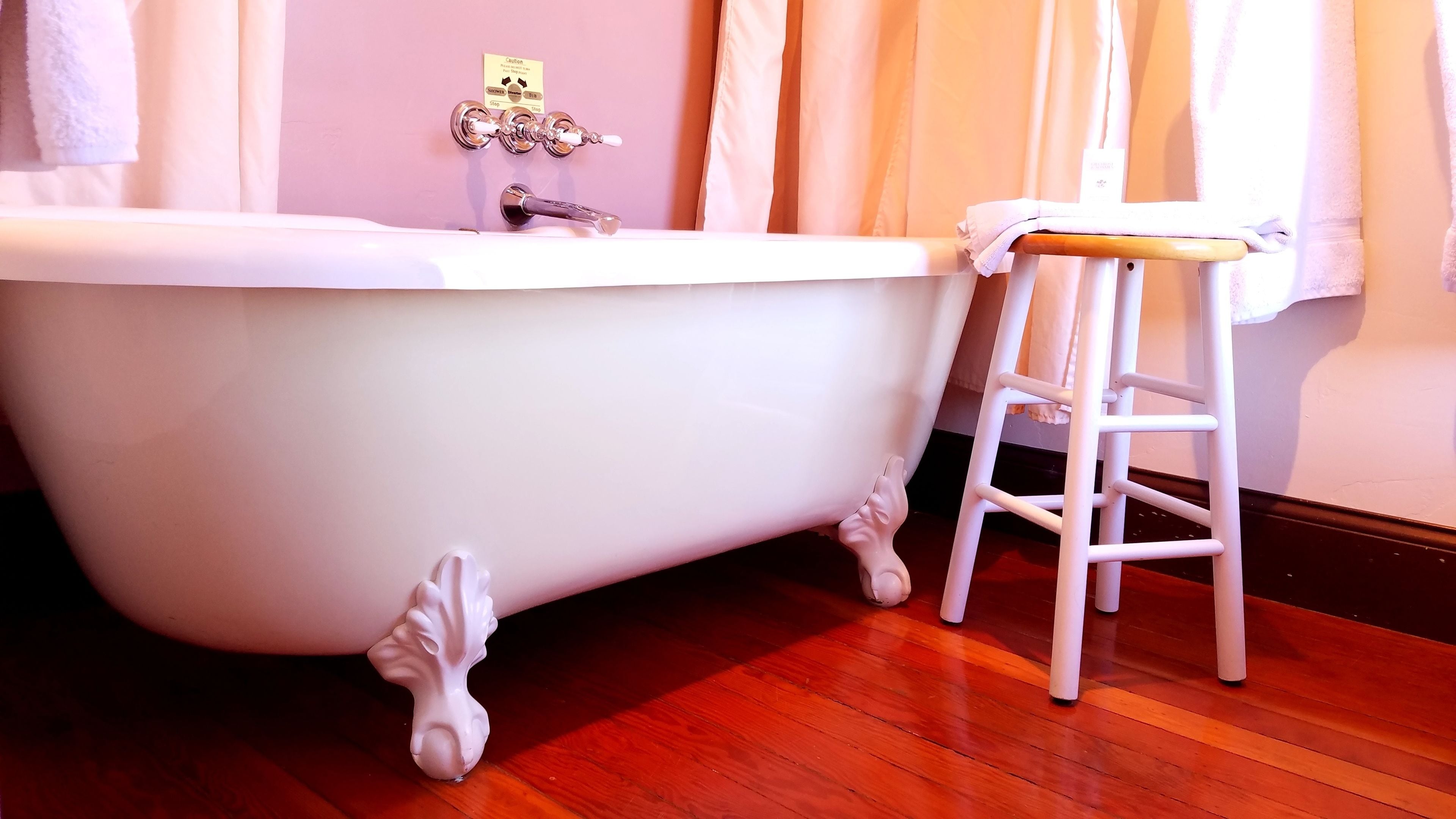 Une salle de bain avec une baignoire blanche, un tabouret en bois et un porte-serviettes.