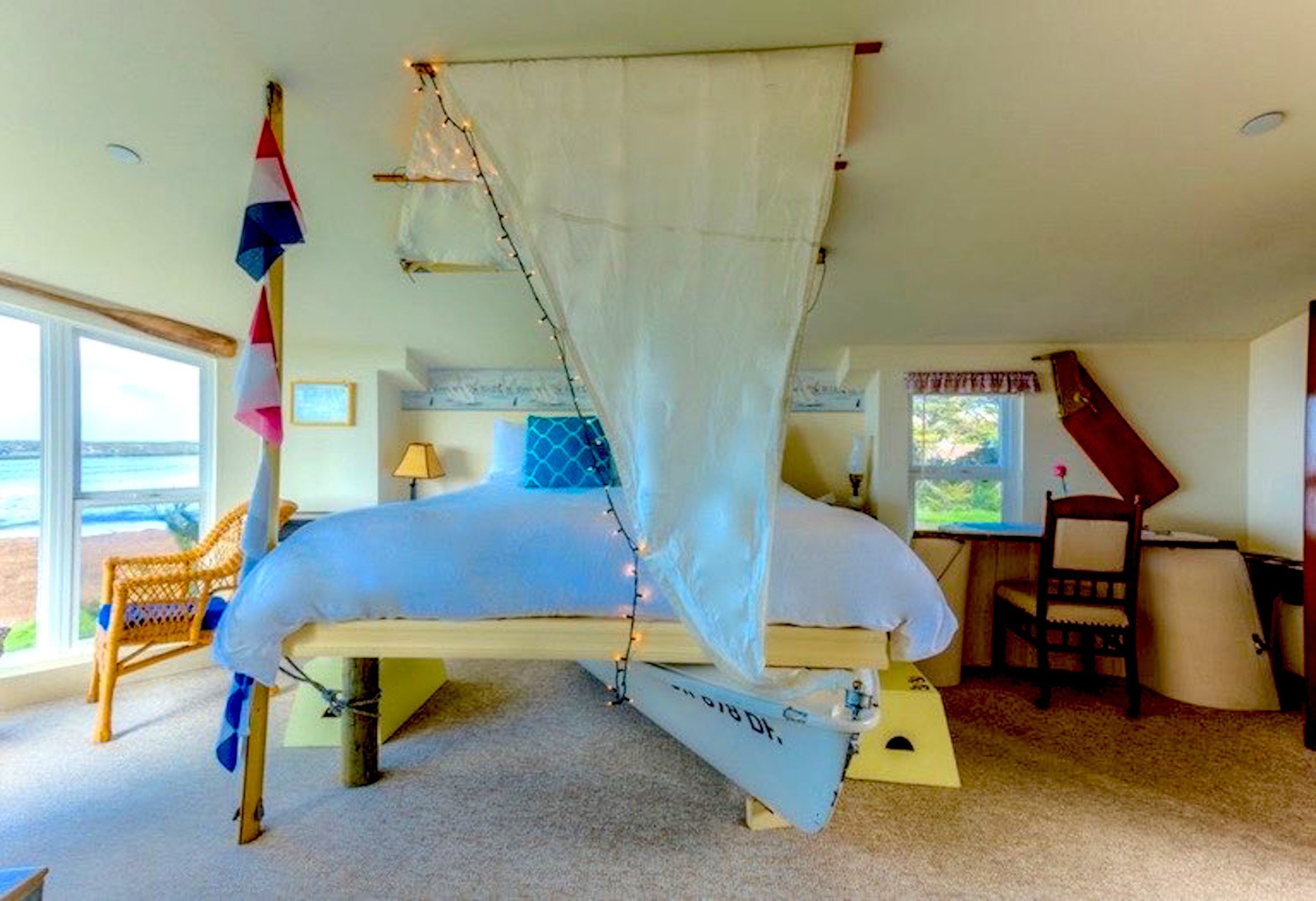 A bedroom with a canopy bed, a chair, a desk, and a view of the outdoors.