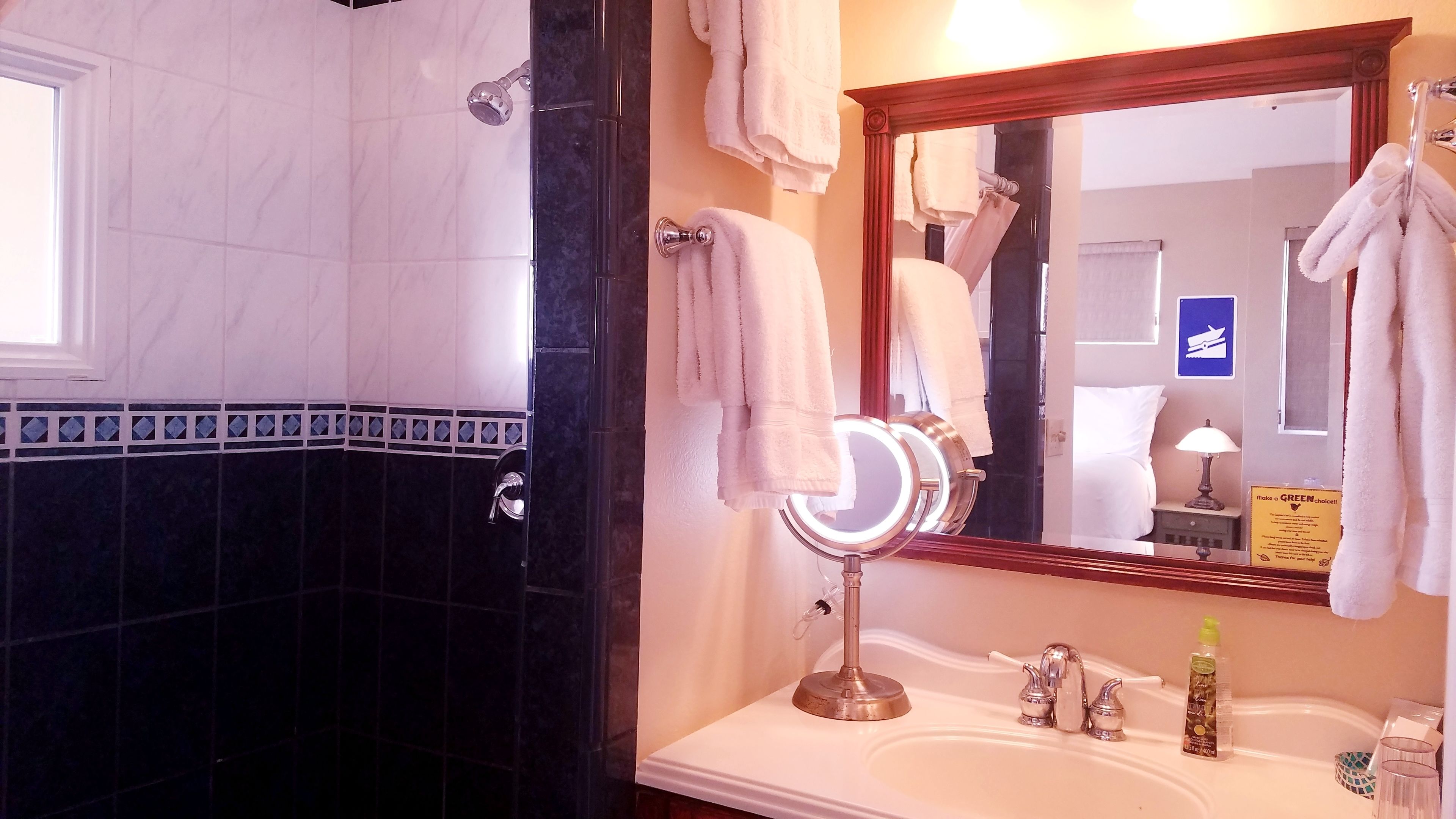 Un baño con lavamanos blanco, espejo y ducha.
