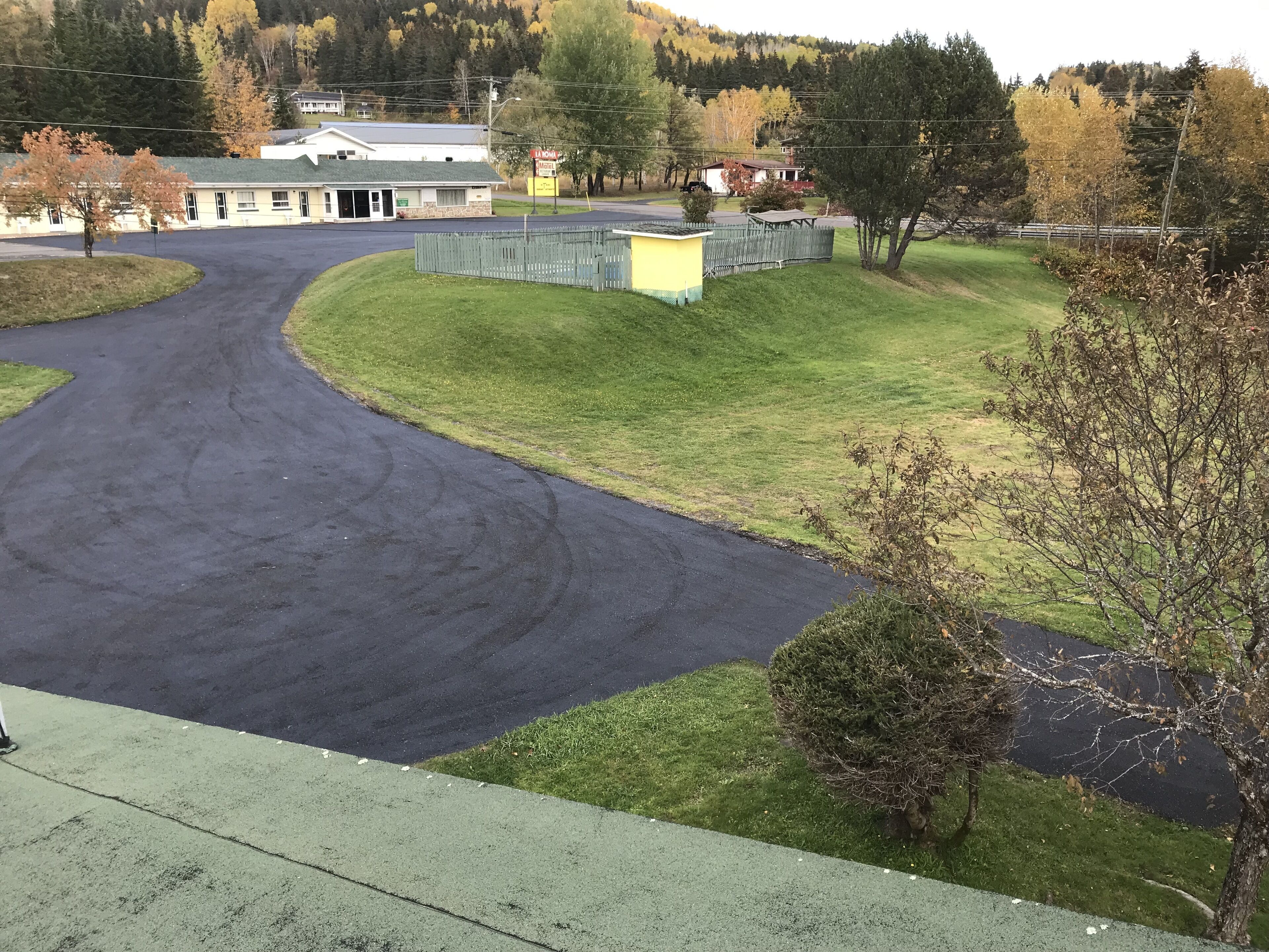 A road curving to the left with a grassy area and a building in the background.