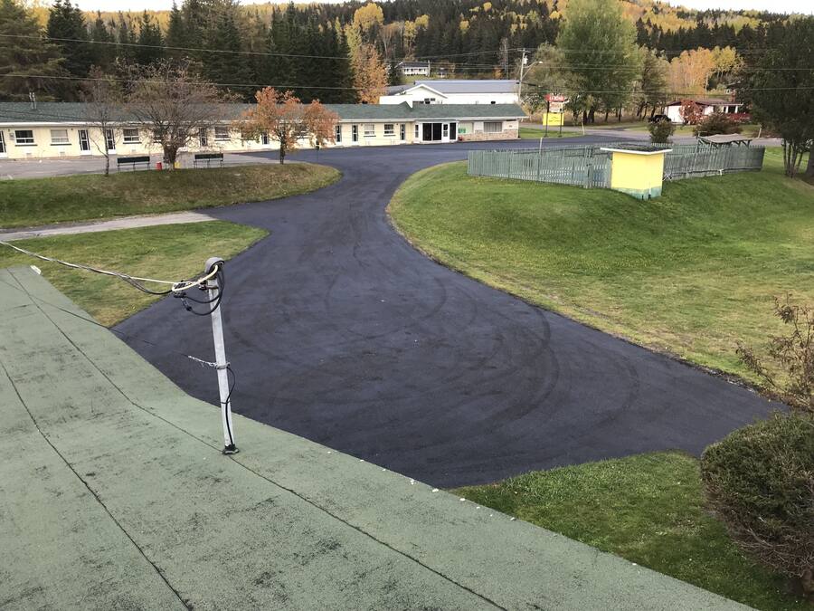 Una carretera pavimentada serpentea por un paisaje verde con un edificio al fondo.