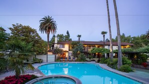 Una piscina rodeada de exuberante vegetación y palmeras, con un edificio al fondo.