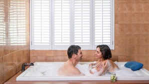 Una pareja en una bañera con una ventana detrás.