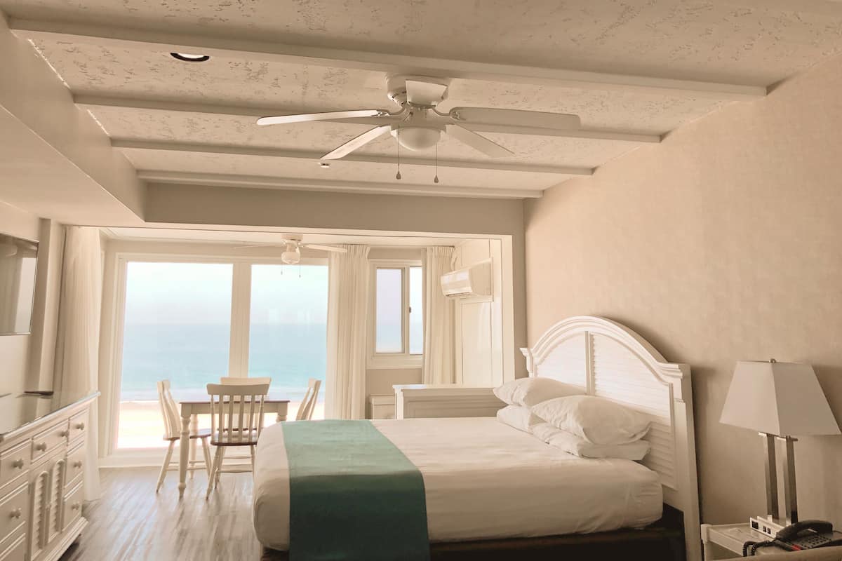 Une chambre à coucher avec un lit, un bureau et une chaise près d’une fenêtre donnant sur un beau paysage.