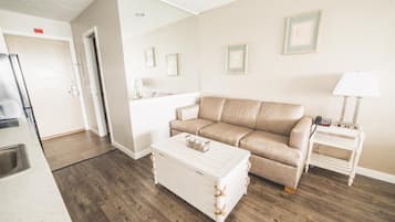 A living room with a beige sofa, a white coffee table, a small white side table, and a lamp.