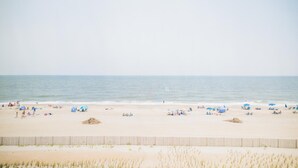 A beach with people, umbrellas, and a fence. - Surf Club Oceanfront Hotel (Dewey Beach)