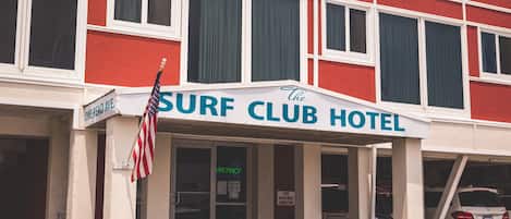Ein Surfhotel mit roter Fassade, weißen Fenstern und einer US-amerikanischen Flagge.