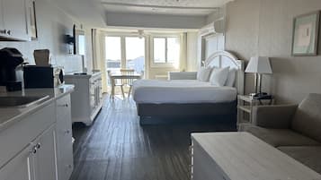 A hotel room with a bed, a desk, a chair, a sofa, a coffee maker, and a television.