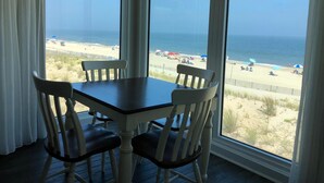 A dining area with a table and chairs, large windows with a beach view. - Surf Club Oceanfront Hotel (Dewey Beach)