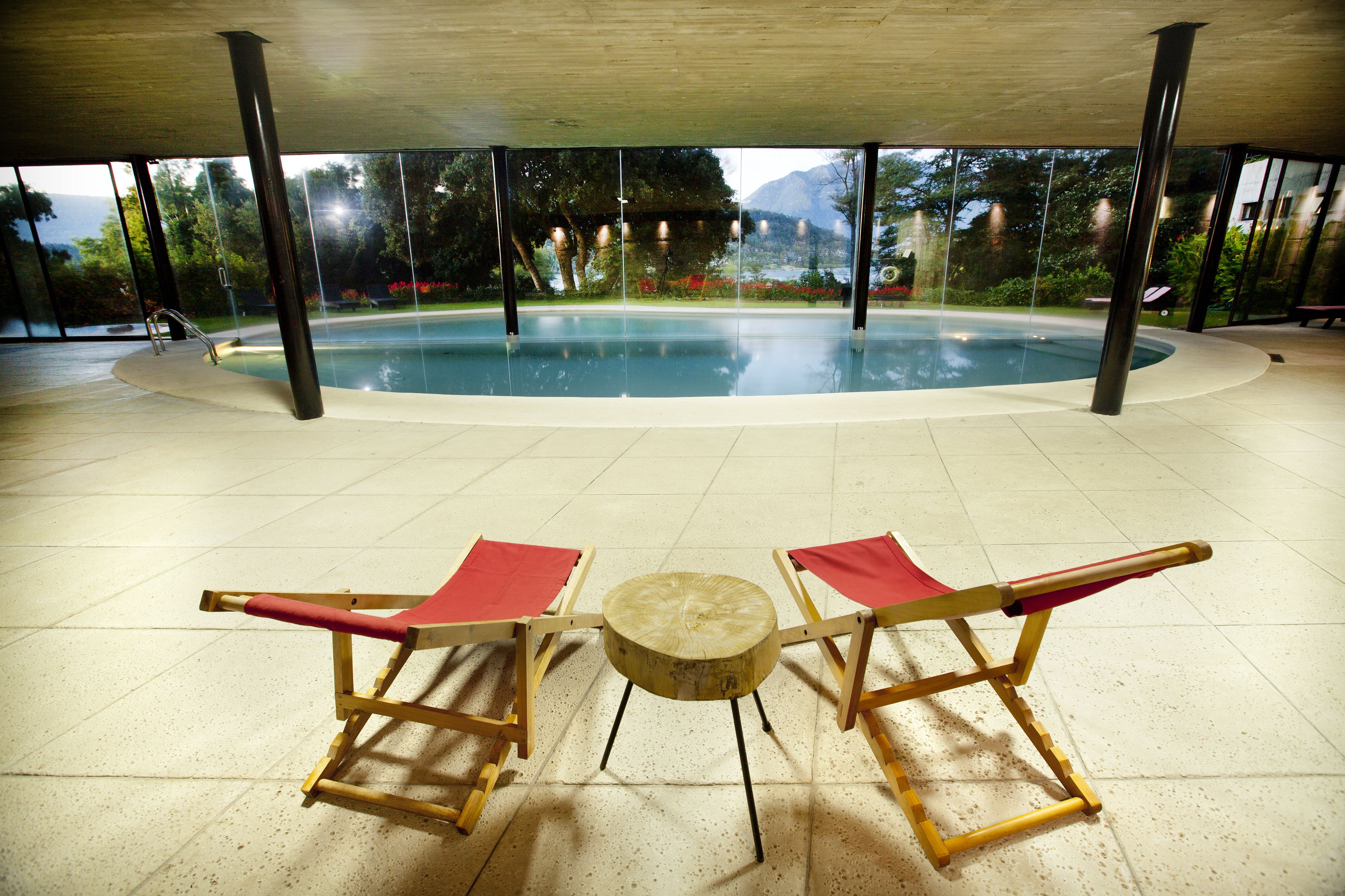 Un área de piscina con dos sillones de descanso y una pequeña mesa redonda.