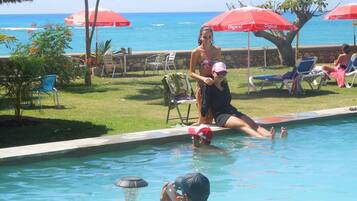Relax by the ocean with a clear view, surrounded by lounge chairs and lush greenery.