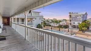 A covered balcony with a pool, overlooking a residential area with houses and a clear sky. - Dry Dock Inn (Carolina Beach)