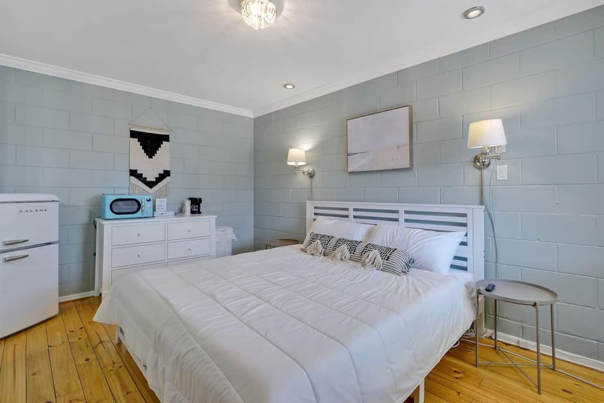 A bedroom with a bed, a dresser, a microwave, and a nightstand.