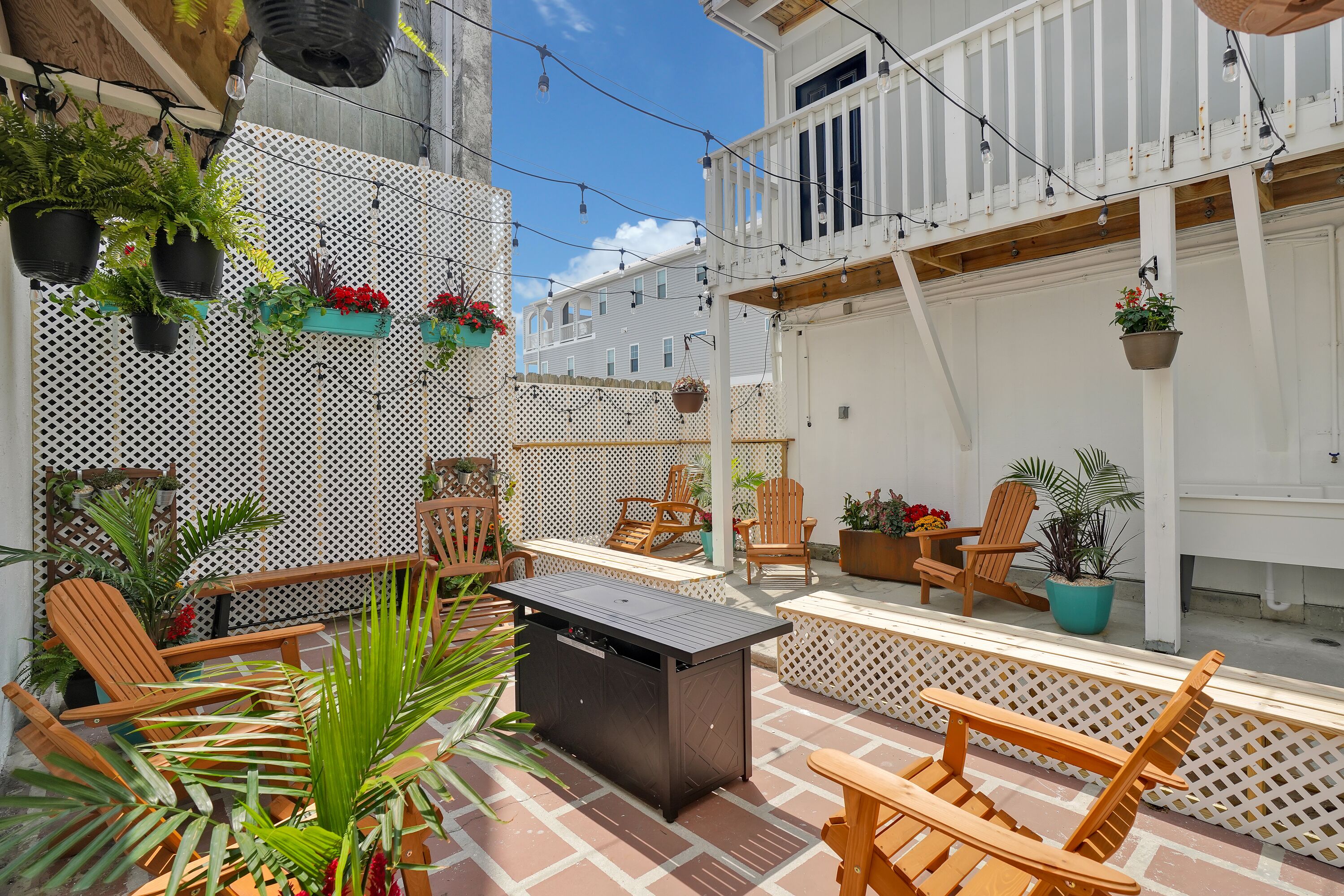 A patio area with wooden chairs, a table, and potted plants.