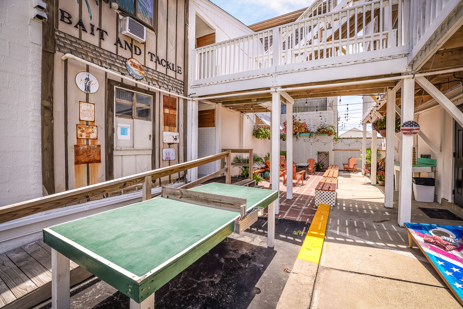 An outdoor seating area with tables and chairs, a covered patio, and a building with a sign reading "BAIT AND TACKLE".
