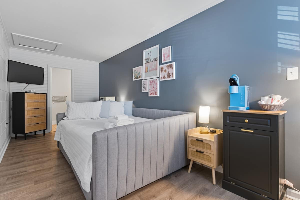A modern bedroom with a bed, bedside tables, a wardrobe, and wall art.