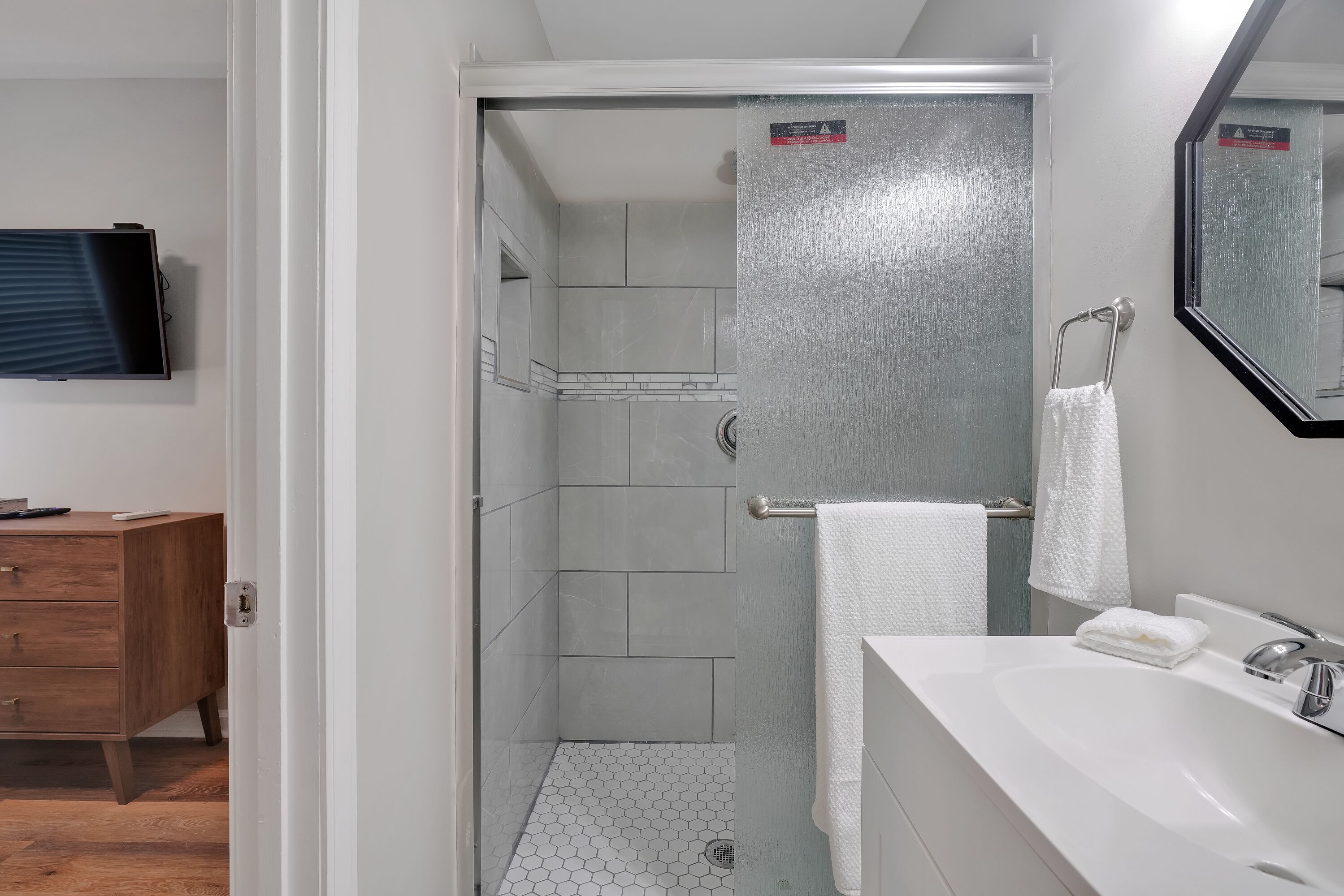 A modern bathroom with a shower, a sink, and a mirror.