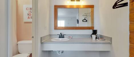 A modern bathroom with a white sink, a mirror with a wooden frame, and a towel rack.