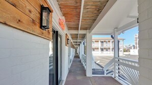 A covered corridor with white brick walls, wooden beams, and a metal railing. - Dry Dock Inn (Carolina Beach)