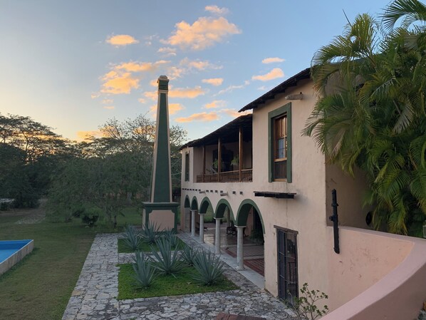 Un edificio con balcón, piscina y jardín con plantas.