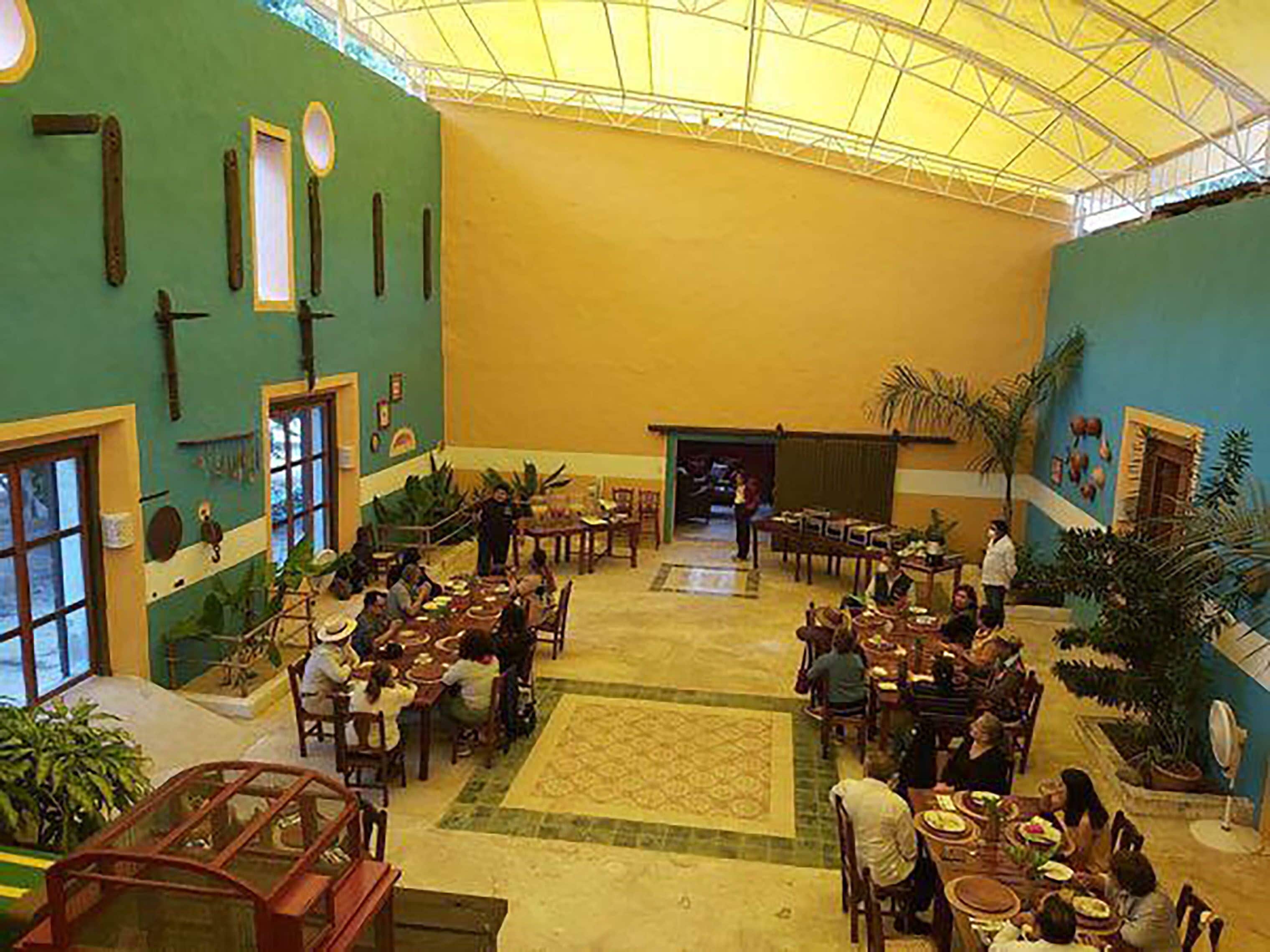 A spacious indoor area with multiple dining tables and chairs, a central open space, and a high ceiling with a skylight.