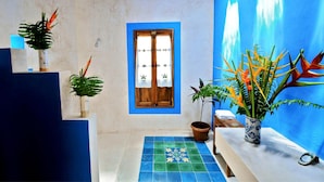 A bathroom with a blue and white color scheme, a window with a wooden frame, and a tiled floor with a decorative pattern. - Hacienda San Francisco (Dzidzantun)