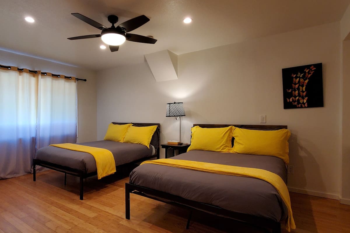 A bedroom with two beds, a ceiling fan, a desk, and a chair.