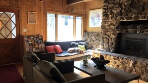 A cozy cabin interior with a stone fireplace, wooden walls, a sofa, and a coffee table. - The Mammoth Inn (Mammoth Lakes)