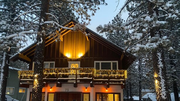 A two-story wooden cabin with a balcony, surrounded by snow-covered trees. - The Mammoth Inn (Mammoth Lakes)