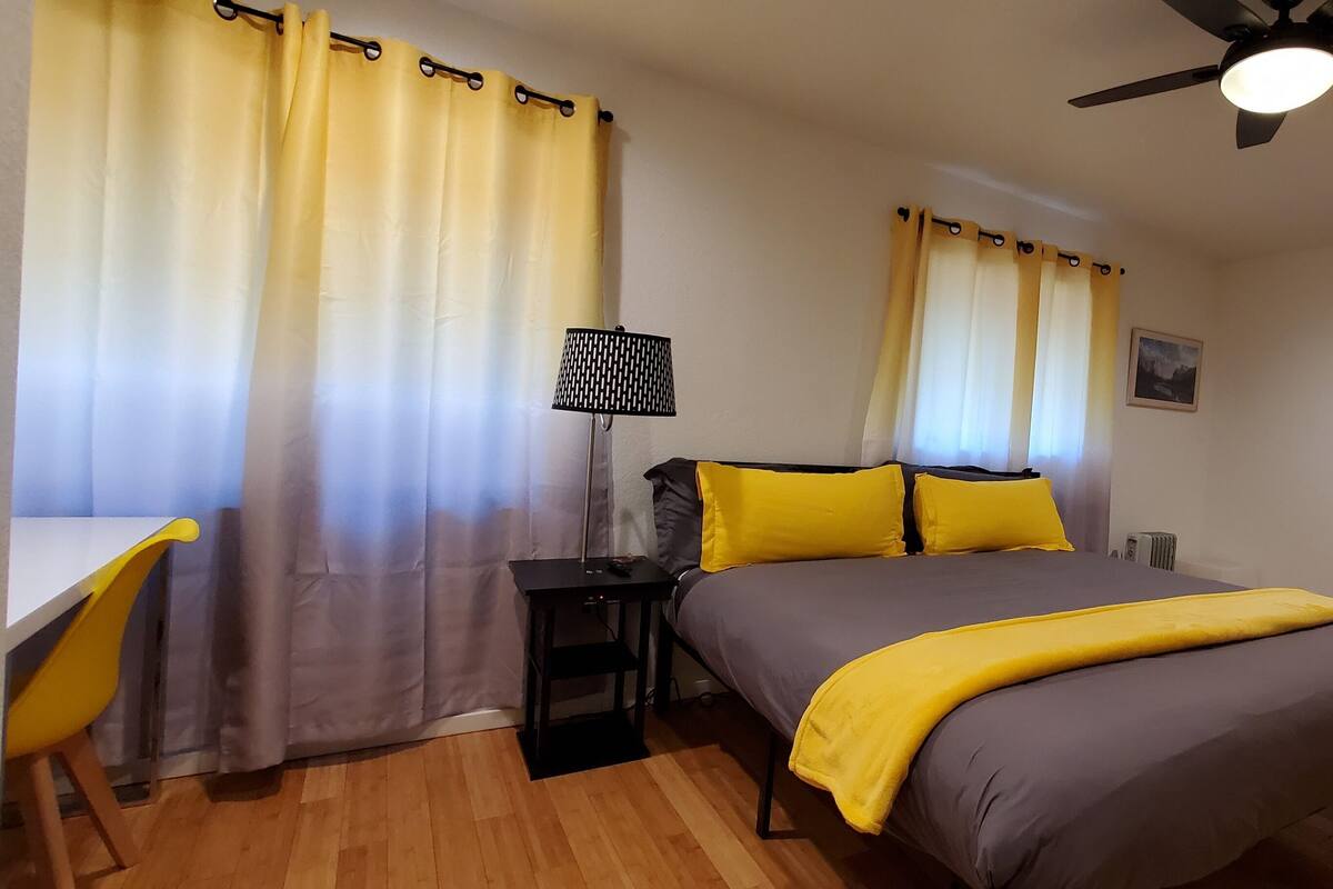 A bedroom with a bed, bedside tables, a lamp, a ceiling fan, and a wardrobe.