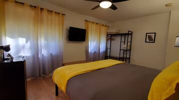 A bedroom with a bed, a desk with a lamp, a TV, and a bunk bed.
