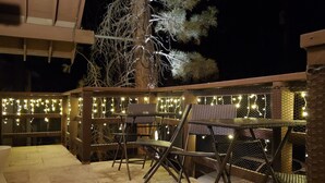 An outdoor patio area with metal chairs and a table, decorated with string lights. - The Mammoth Inn (Mammoth Lakes)