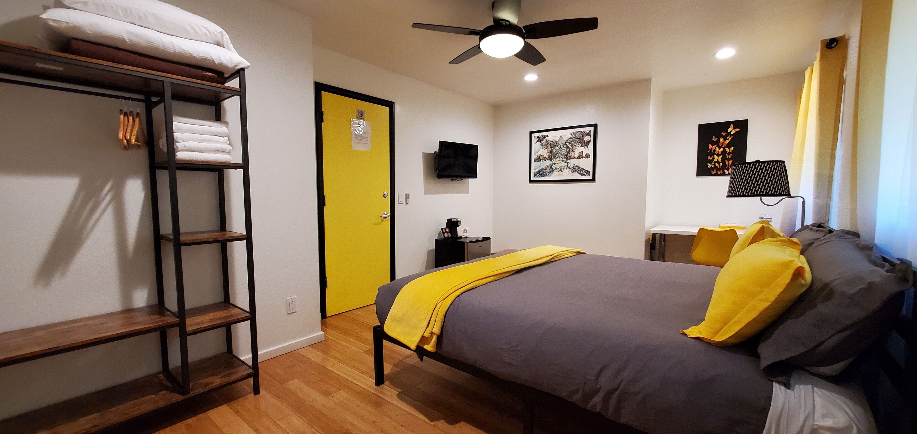 Een slaapkamer met een bed, een kledingkast, een plafondventilator en een deur.