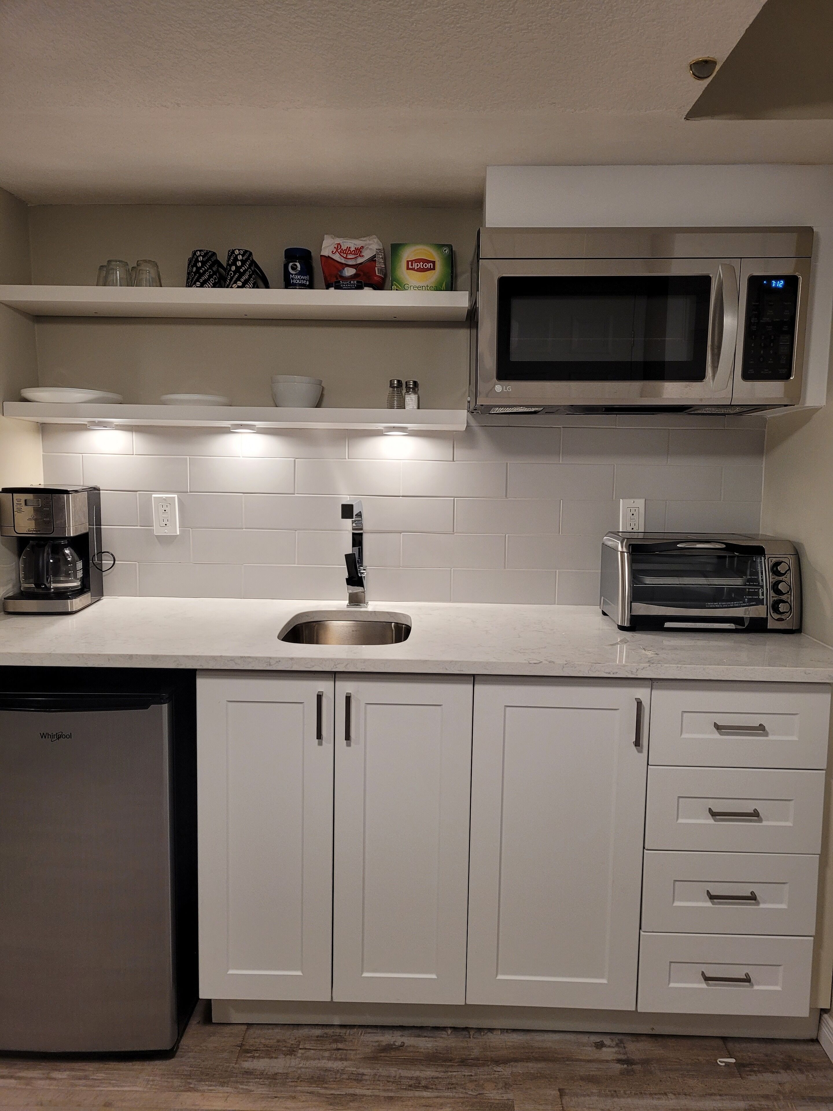 A modern kitchen with white cabinets, a stainless steel sink, a microwave, a toaster, and a dishwasher.