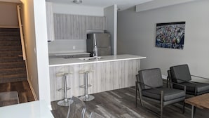 Una cocina moderna con refrigerador empotrado, una barra con taburetes y una mesa de comedor con sillas.