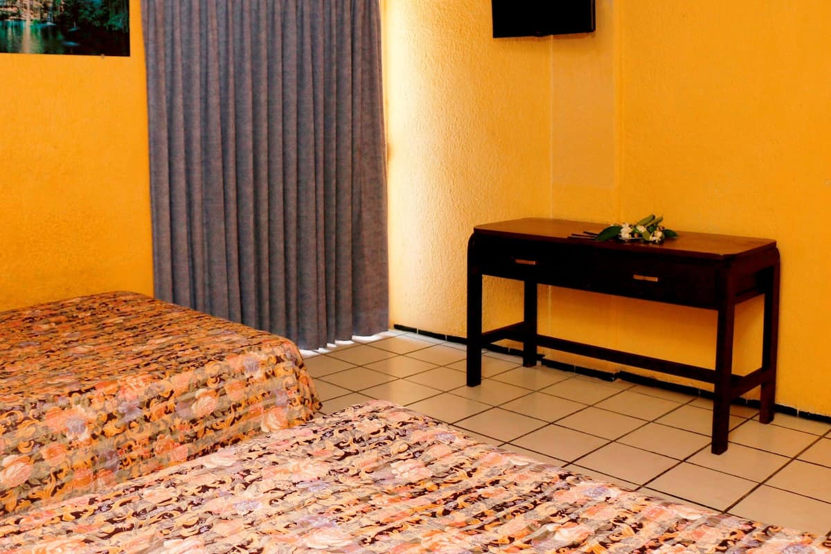 A hotel room with two beds, a flat-screen TV mounted on the wall, and a small wooden table.