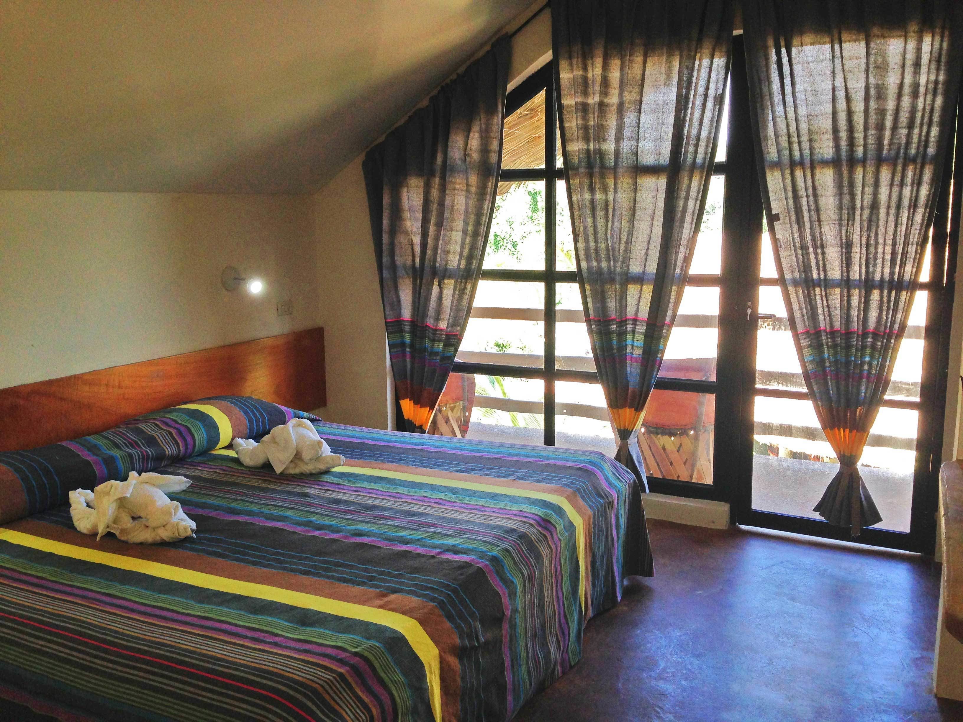 A room with a large bed, a wooden headboard, and sheer curtains.