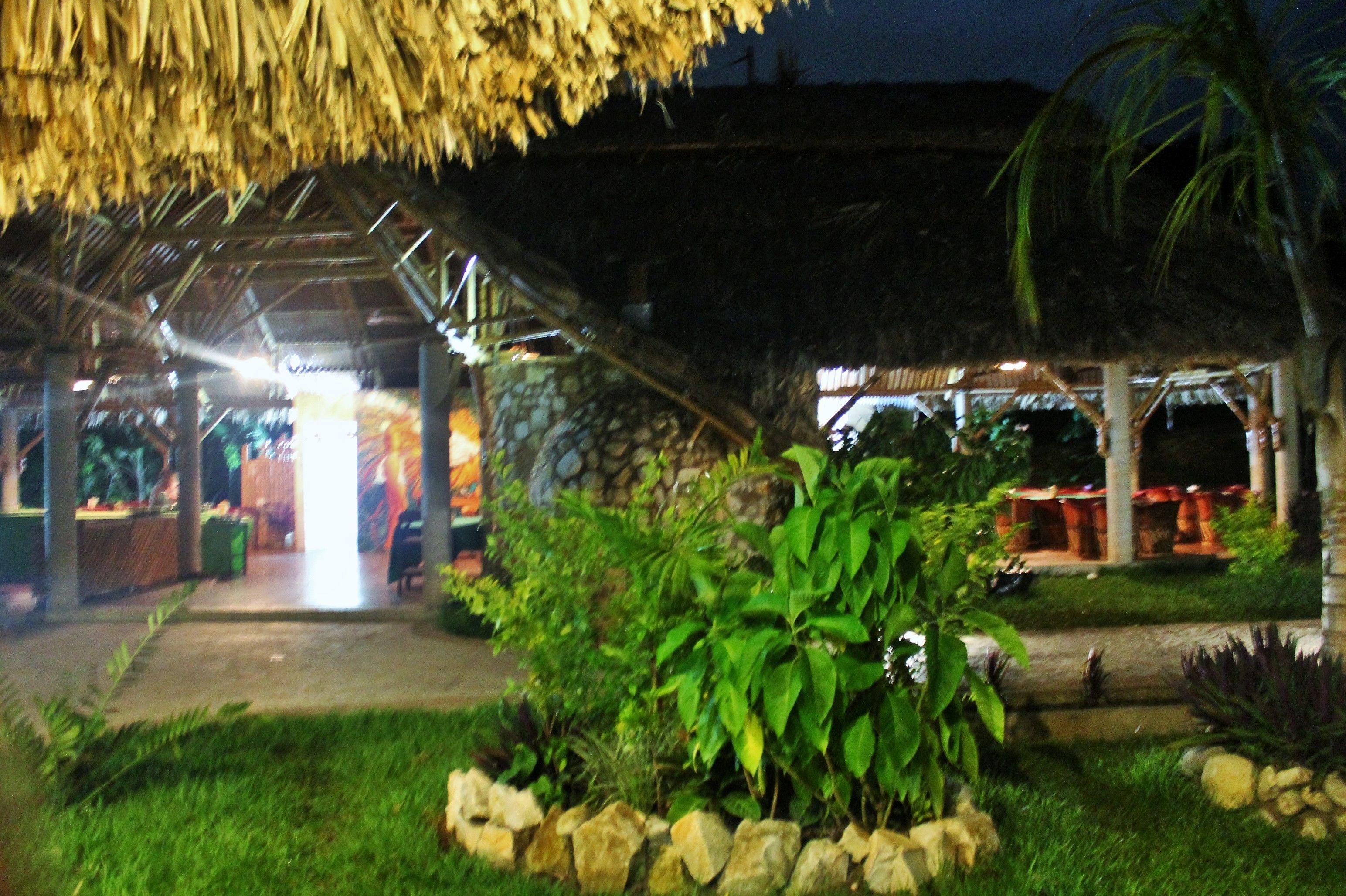 A thatched-roof structure with a covered walkway leading to a building.