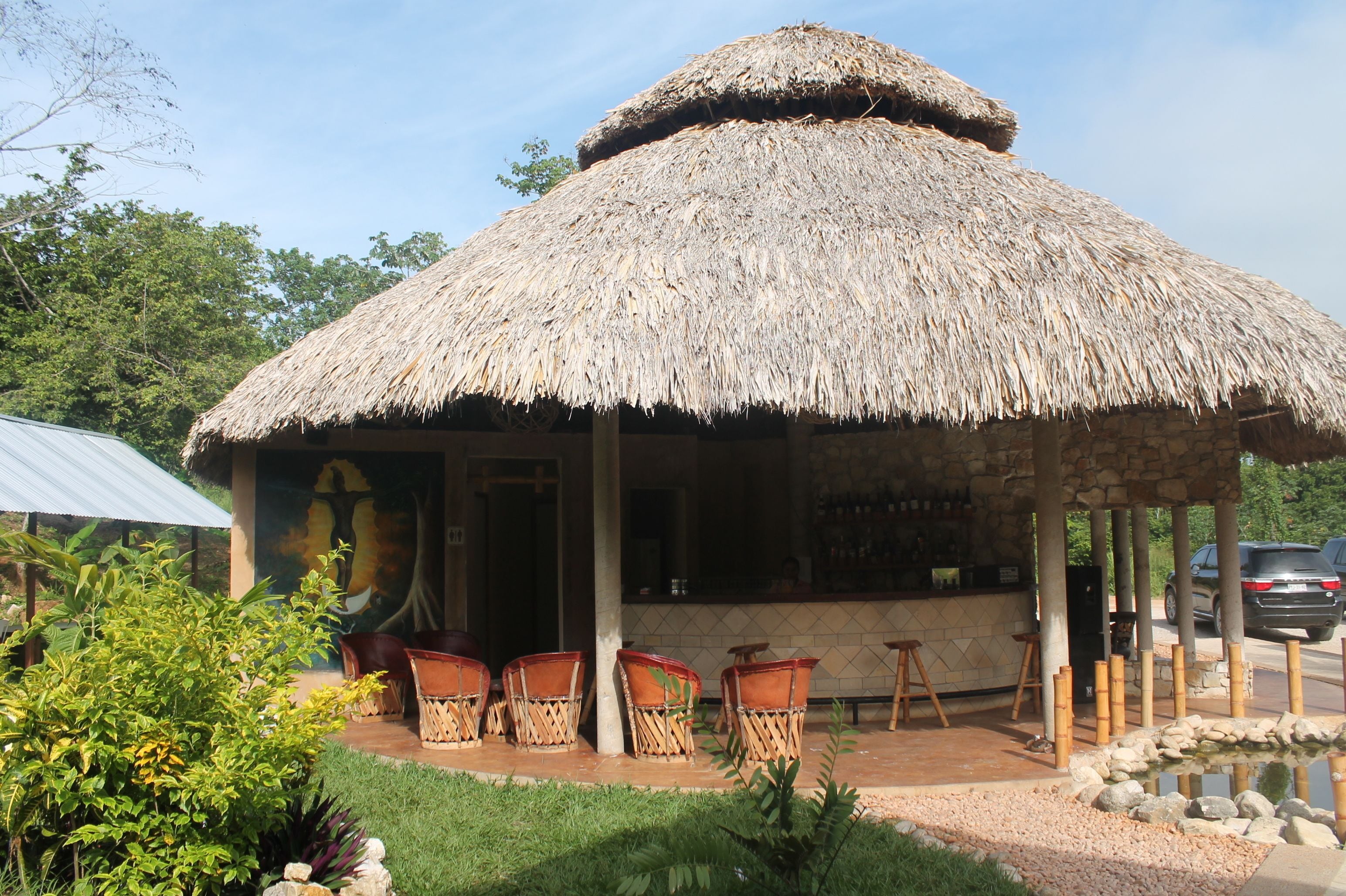 A thatched-roof structure with outdoor seating and a bar area.