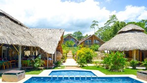 Un área de piscina con construcciones de techo de paja y una vista despejada de la piscina.