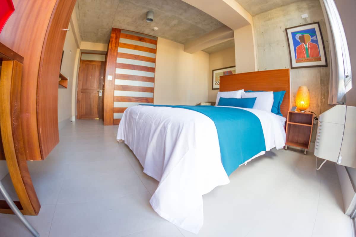 Ein Hotelzimmer mit einem großen Bett, einem Holz-Kopfteil, einem Nachttisch mit Lampe und einem gerahmten Bild an der Wand.