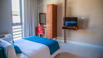 A hotel room with a bed, a TV, a desk, and a chair.