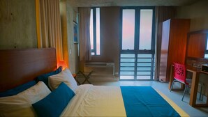 A hotel room with a bed, a desk, a chair, and a window with a view. - Dream Inn PR (San Juan)