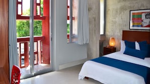 A bedroom with a bed, a nightstand, a lamp, a window, and a door leading to an outdoor area. - Dream Inn PR (San Juan)