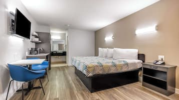 Una habitación de hotel moderna con cama, escritorio, silla, televisión y mesita de noche.