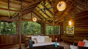 A wooden interior with a sofa, coffee table, and wicker chairs. - La Finca Chica (Cahuita)