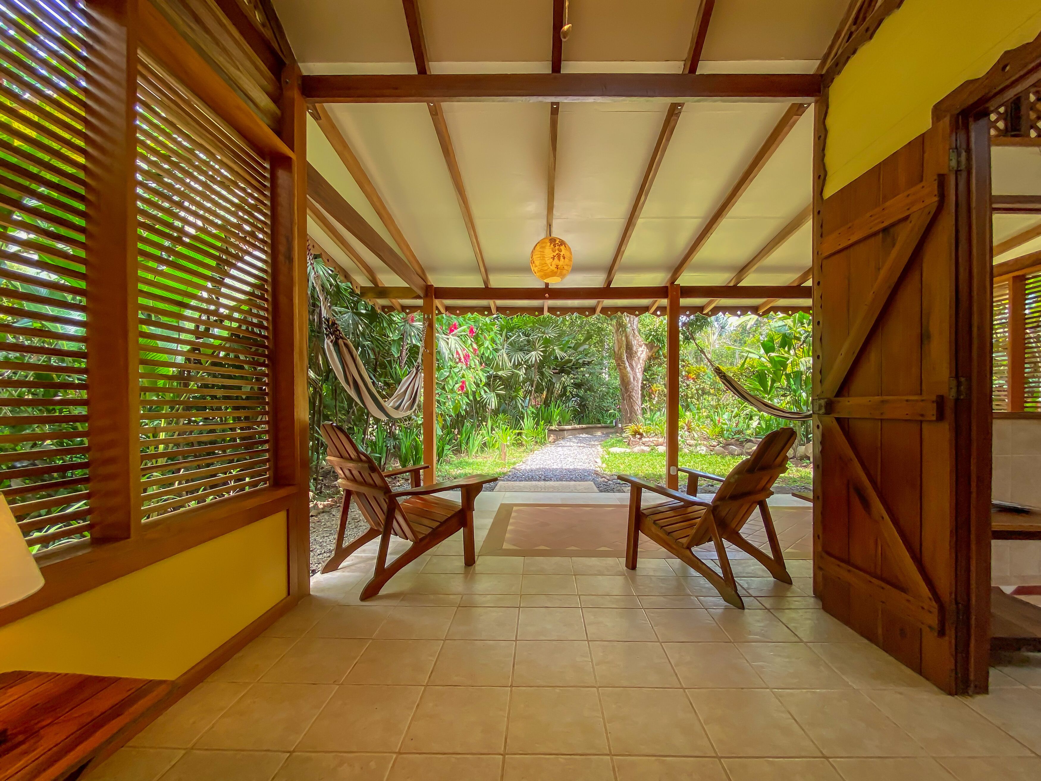 A covered patio with wooden furniture and a hammock.