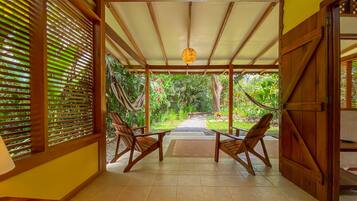 A covered patio with wooden furniture and a hammock.